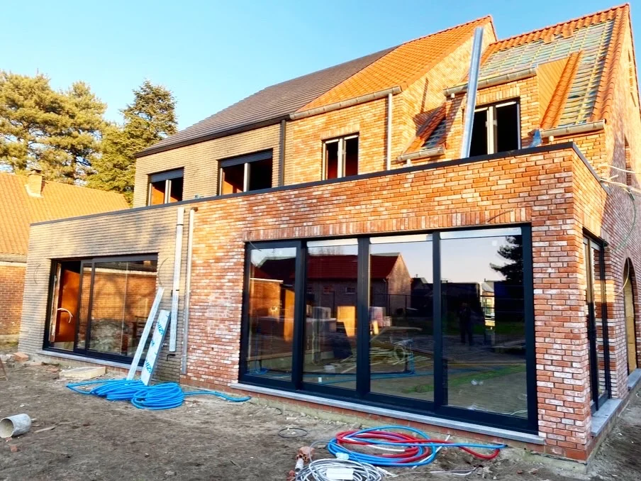 Woning in aanbouw met zwarte ramen en grote glaspartijen
