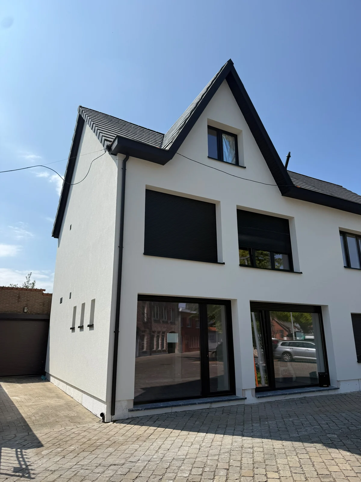 Witte woning met zwarte raamkaders en glazen benedenverdieping