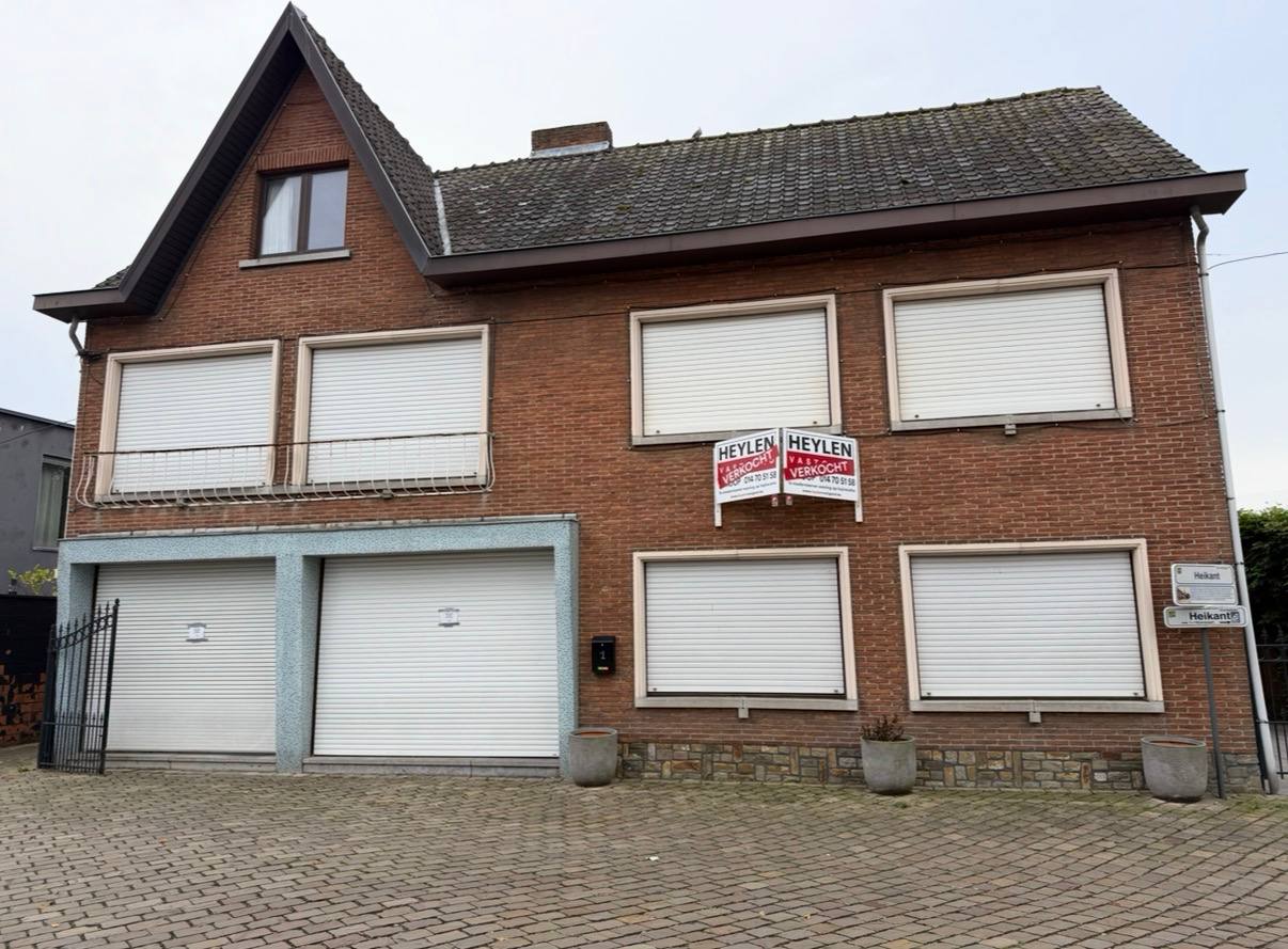 Bakstenen voorgevel met bestaande ramen en witte rolluiken vóór de renovatie